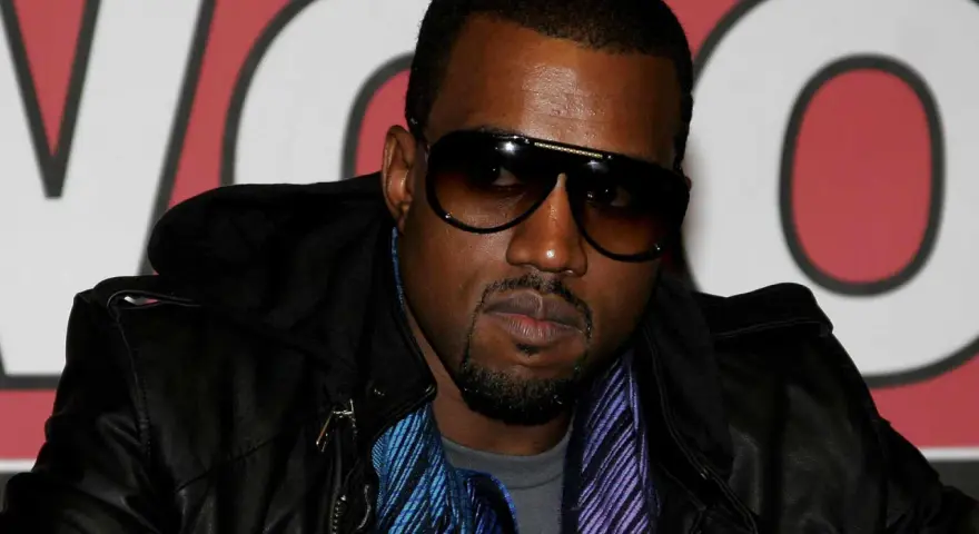 Kanye West w okularach przeciwsłonecznych i skórzanej kurtce, gotowy na koncert w Polsce.