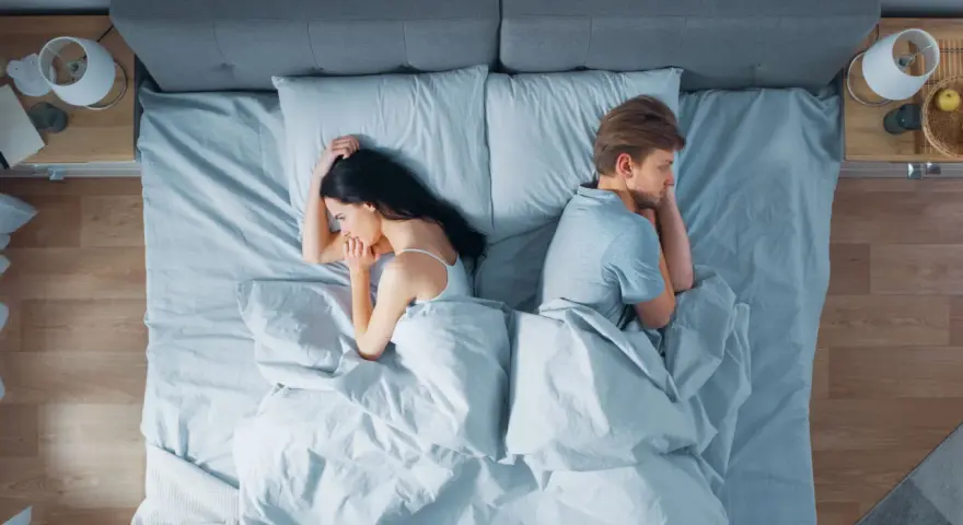 Ein Paar liegt im Bett, jeder auf seiner Seite, die Rücken einander zugewandt. Getrennte Schlafzimmer – der Anfang vom Ende?