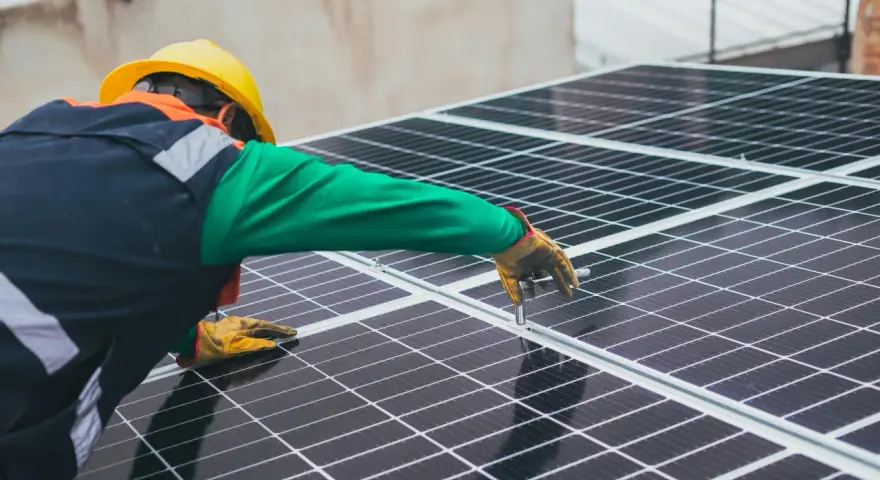 Handwerker mit gelbem Helm montiert Solarmodule für solarstrom einspeisen.