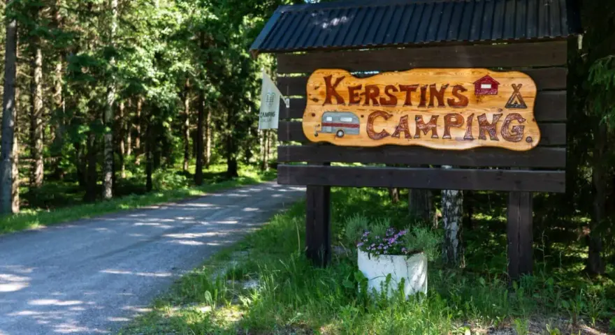 Välkommen till Kerstins Camping! En skylt i trä visar vägen till en lugn plats i skogen.