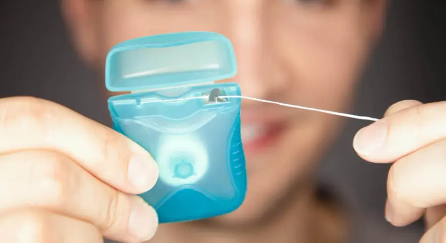 Mężczyzna trzyma niebieskie pudełko z białą nicią dentystyczną. To świetna alternatywa, co zamiast nici dentystycznej, gdy potrzebujesz czystości.