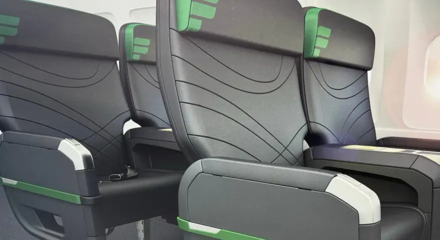 Rows of black airplane seats with green accents. Does Frontier have first class? These seats look comfortable, but it's unclear if they are first class.