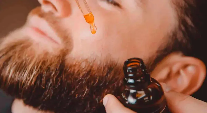Un hombre aplica aceite con un gotero a su barba. Un secreto para tener una barba bonita y cuidada.