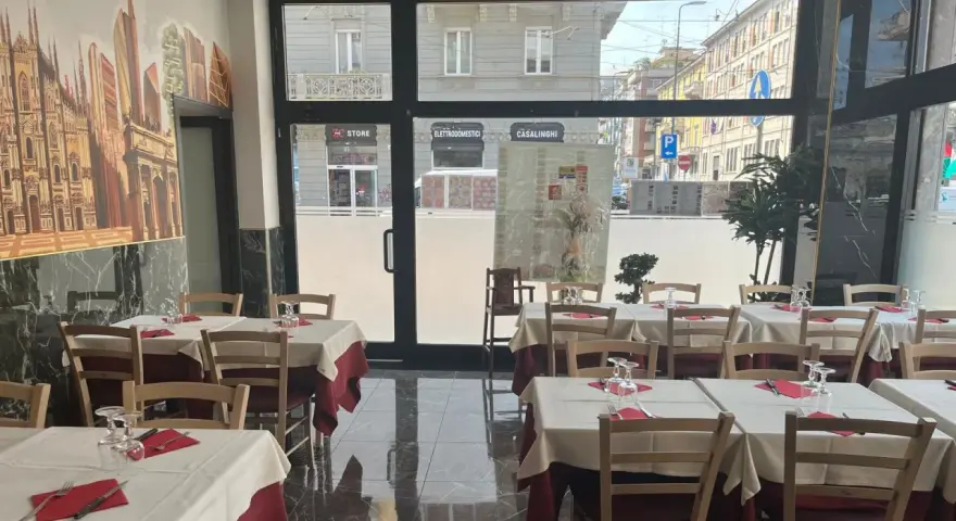 Restaurant interior with tables set for dining, featuring a mural of Milan's skyline.