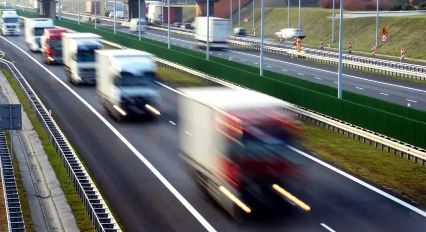 Ciężarówki na autostradzie, rozmyte przez ruch. Kierowcy potrzebują pauzy, by odpocząć od długiej jazdy.