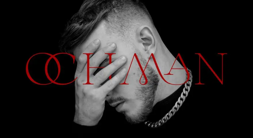 Krystian Ochman - nowa płyta. Artysta z dłonią na twarzy, w tle czerwony napis "OCHMAN".