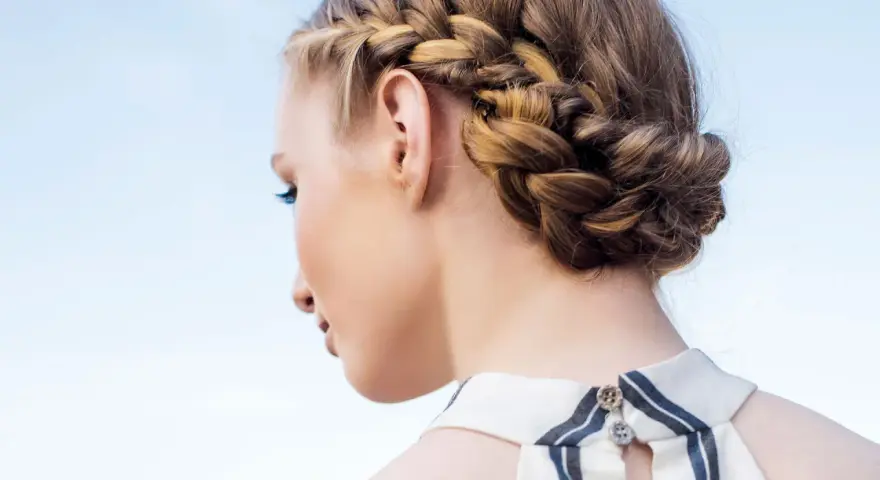 Peinados con trenzas: una mujer con un recogido trenzado elegante, ideal para un día soleado.