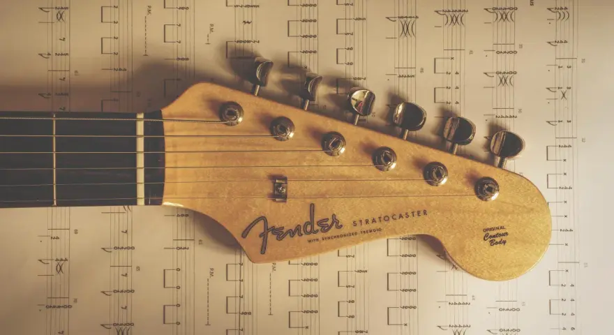 Głowa gitary Fender Stratocaster na tle nut. Idealne nuty na gitarę dla początkujących.