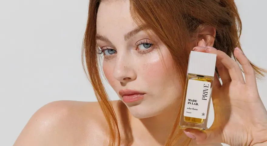 Ruda kobieta z niebieskimi oczami prezentuje perfumy "Made in Lab". Opinie o nich są zachęcające.