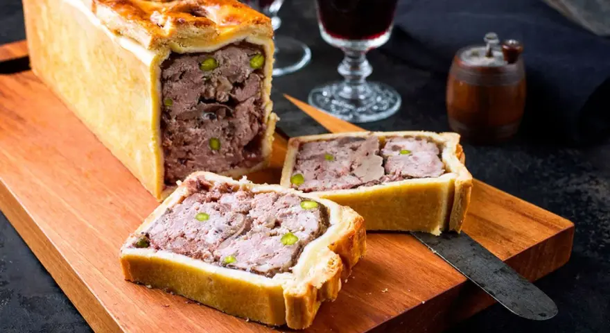 Deliciosa pate en croute receta, un pastel de carne jugoso y sabroso, listo para ser cortado y disfrutado.