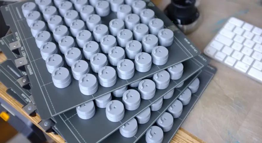 Stosy szarych, cylindrycznych elementów, świeżo po prototypowaniu 3d. Obok klawiatura i kałamarz.