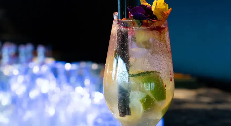 Orzeźwiający drink prosecco sprite z limonką i kwiatową dekoracją, idealny na letnie wieczory.