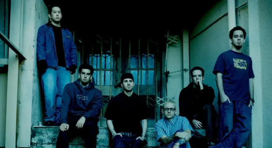 Sześciu członków zespołu Linkin Park, w tym Chester Bennington, pozuje na schodach.