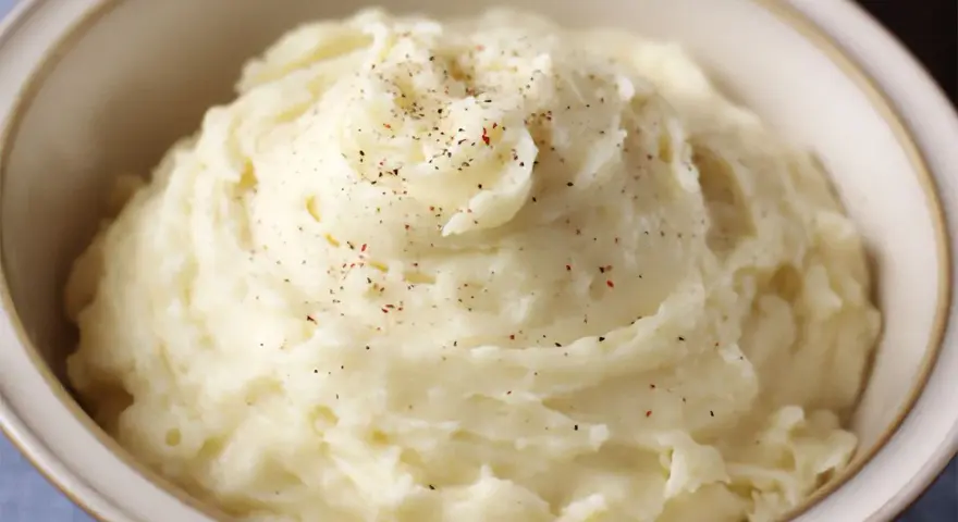 Un cremoso puré de patatas, espolvoreado con pimienta negra y roja, servido en un cuenco.
