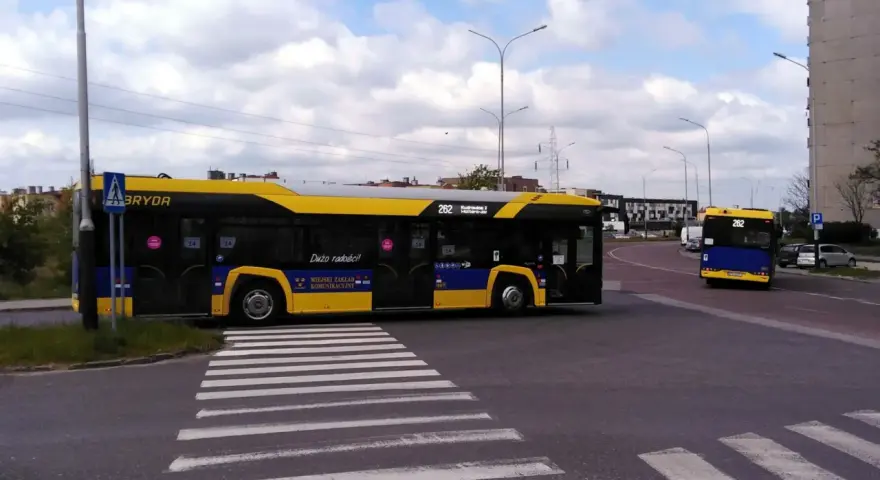 Autobus 262 z napisem "Dużo radości!" zbliża się do przejścia dla pieszych. Sprawdź autobus 136 rozkład jazdy.