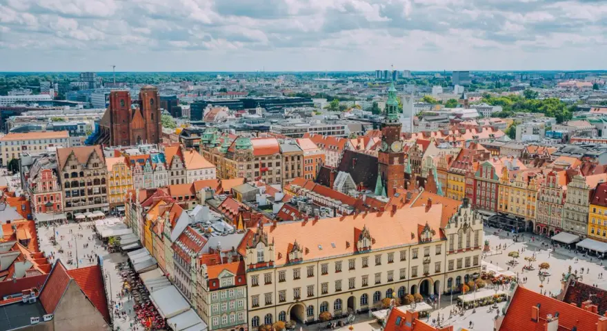 Wrocław słynie z kolorowych kamienic na Rynku i wież kościelnych. Widok z lotu ptaka na tętniące życiem miasto.