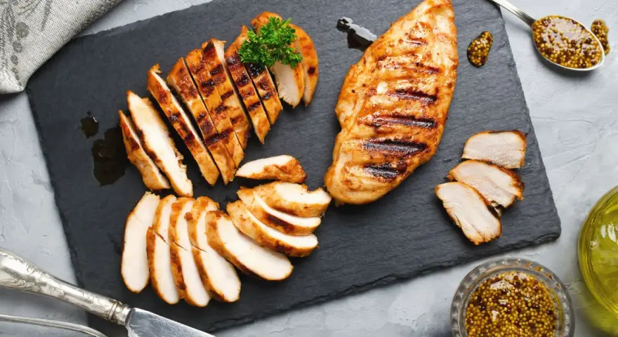 Deliziosa tagliata di pollo grigliata, servita su ardesia con senape e prezzemolo.