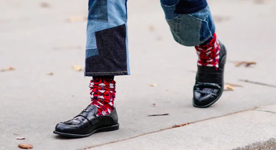 Pantaloni patchwork e scarpe eleganti con calzini rossi a fantasia, un look audace per sfidare le scarpe senza calze in inverno.