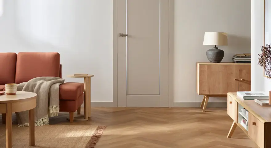 Nowoczesne wykończenie drzwi wewnętrznych w stonowanym kolorze, idealnie komponuje się z drewnianą podłogą i meblami.