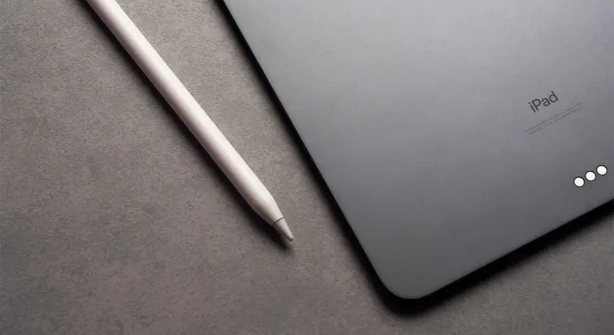 Apple Pencil liegt neben einem iPad mit drei leuchtenden Punkten.