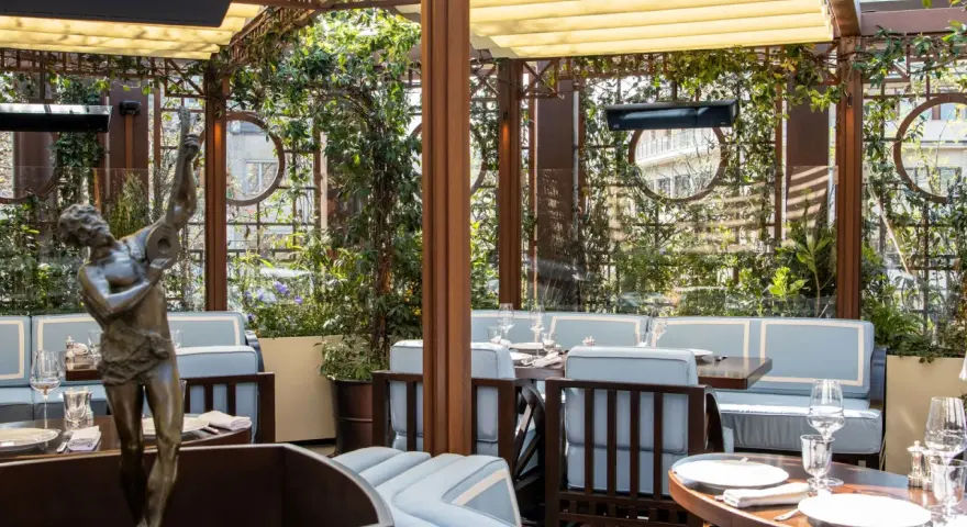 Terrazza lussuosa con statue e piante, tavoli apparecchiati per un'esperienza culinaria al **Wilde Milano**.