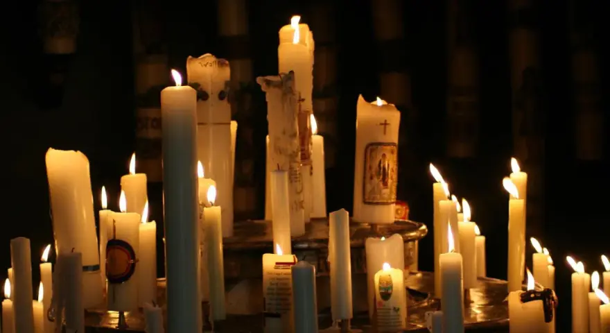 Viele Kerzen brennen in der Dunkelheit, einige mit Bildern und Kreuzen verziert. Ein stimmungsvolles Bild, das an Maria Lichtmess erinnert.