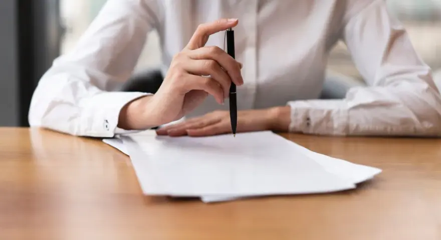 Mano con bolígrafo sobre papeles, revisando documentos. Quizás para resolver el lío de que he heredado una casa sin escrituras.