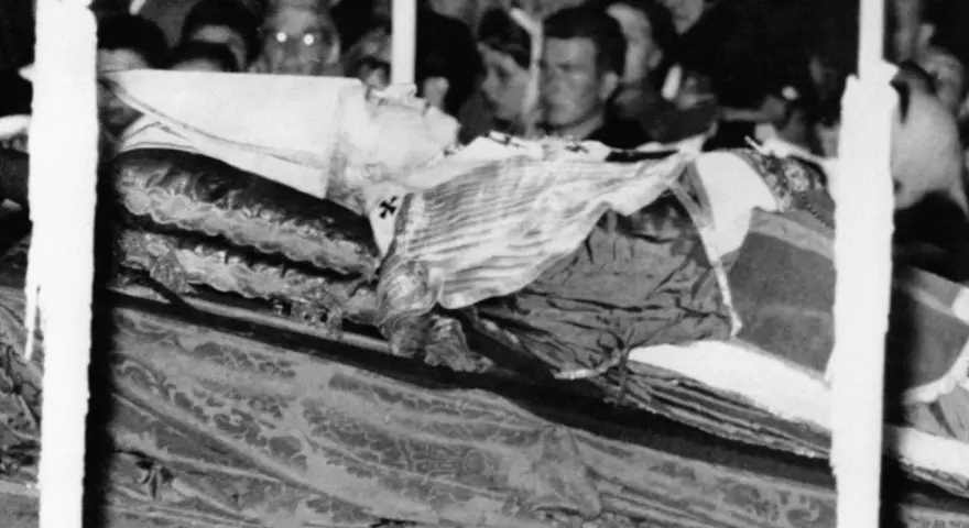 Pius XII w szatach, przygotowany do balsamowania. Tłum ludzi w tle.