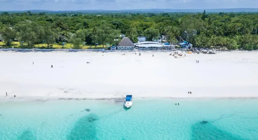 Idealne kenia wakacje: biała plaża, turkusowa woda, łódź i tropikalna roślinność.