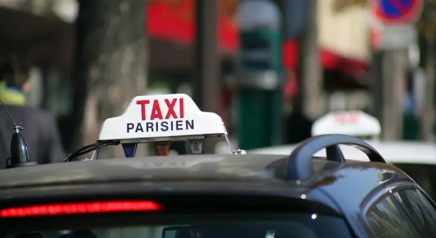 Ein Taxi in Frankreich, mit der Aufschrift "TAXI PARISIEN", wartet auf Fahrgäste.