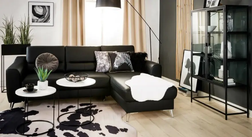 Nowoczesny salon z czarną kanapą i dywanem w cętki. Inspiracje dla odważnych aranżacji.