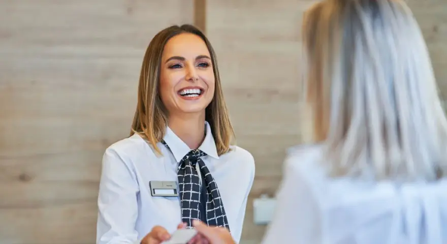 Una sorridente hostess di terra consegna una tessera a un cliente.