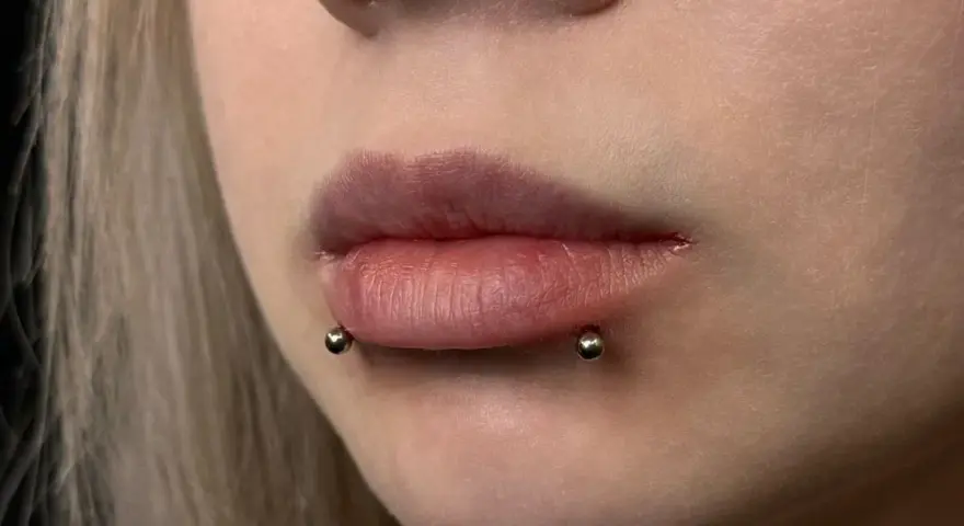Cyber bites piercing na ustach, podkreślający ich kształt.