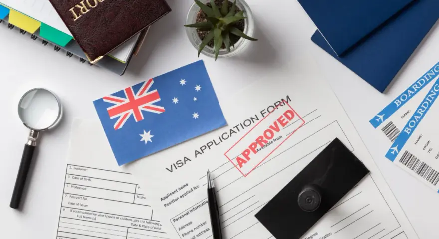 Paszport, formularz wizowy z pieczątką "APPROVED", flaga Australii, bilety lotnicze.