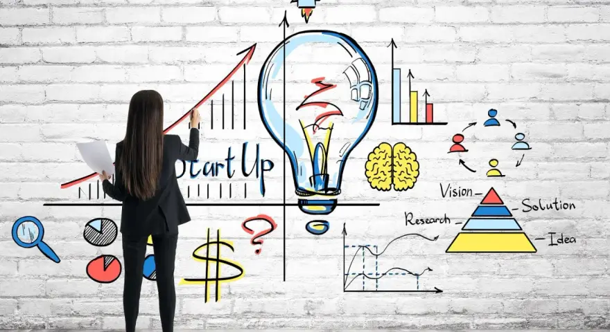 Mujer dibuja un gráfico de crecimiento y una bombilla, simbolizando cómo capitalizar el paro con una idea de startup.