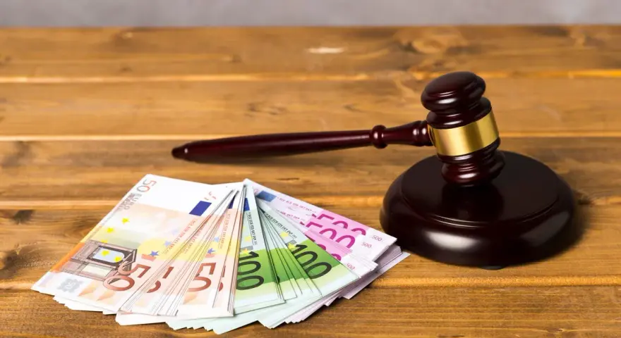 Ein Richterhammer liegt neben Euro-Scheinen. Die Frage "wie lange muss eine Rechtsschutzversicherung bestehen?" wird hier visuell thematisiert.