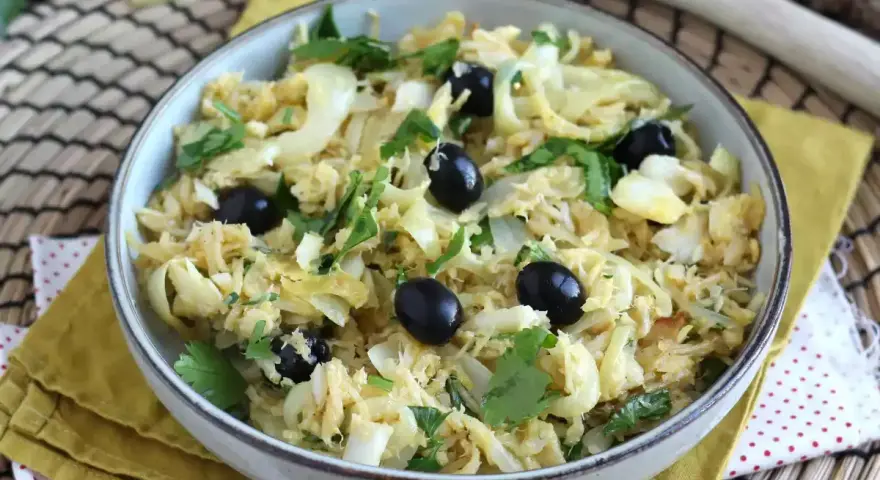 Delicioso bacalao a bras, desmenuzado con patatas finas, huevo y aceitunas negras, adornado con perejil fresco.