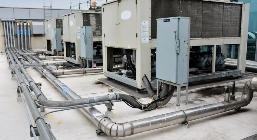 Unidades de aire acondicionado industriales en una azotea, con tuberías de ventilación y aire acondicionado (HVAC) conectadas.