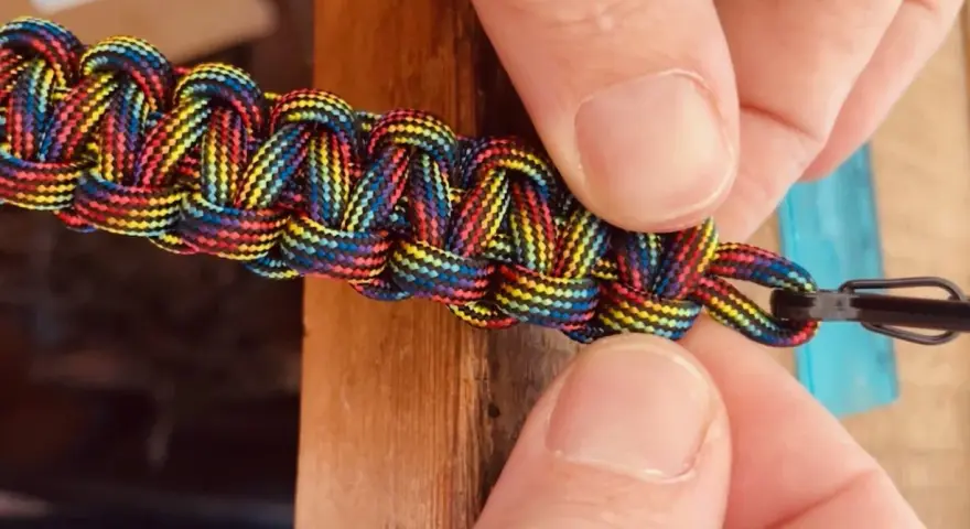 Mani che creano nodi per braccialetti elastici color arcobaleno, un'arte che unisce creatività e praticità.