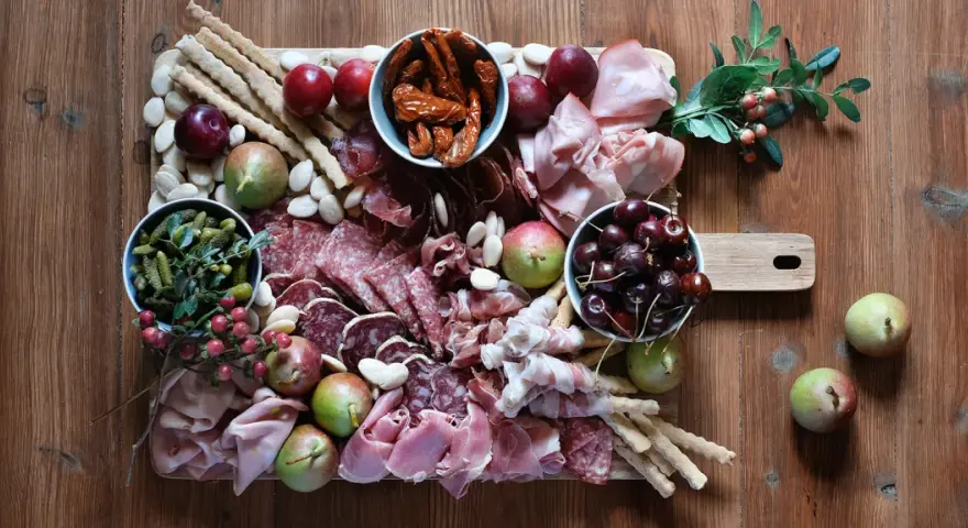 Un invitante tagliere fai da te con salumi, formaggi, frutta, sottaceti e grissini, pronto per essere gustato.