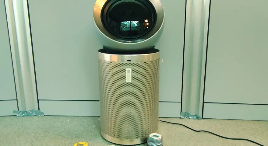 Nowoczesne oczyszczarki powietrza i sprzęt pomiarowy. Urządzenie z okrągłą górą i perforowanym cylindrem, obok taśma miernicza, miernik i inne akcesoria.