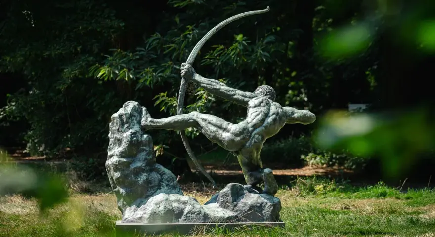 La sculpture de l'archer, une œuvre d'Antoine Bourdelle, se dresse fièrement dans un jardin verdoyant, capturant l'instant d'une tension parfaite.