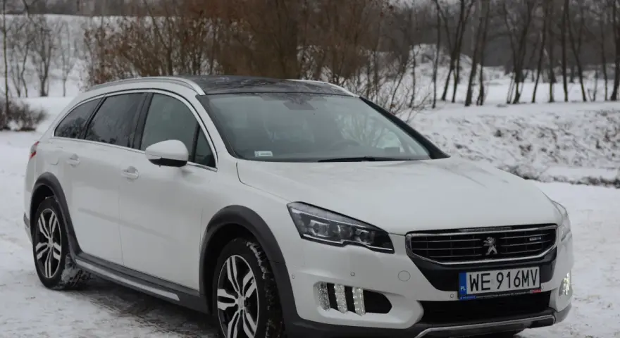Biały Peugeot 508 RXH na śniegu, gotowy na zimowe wyzwania.