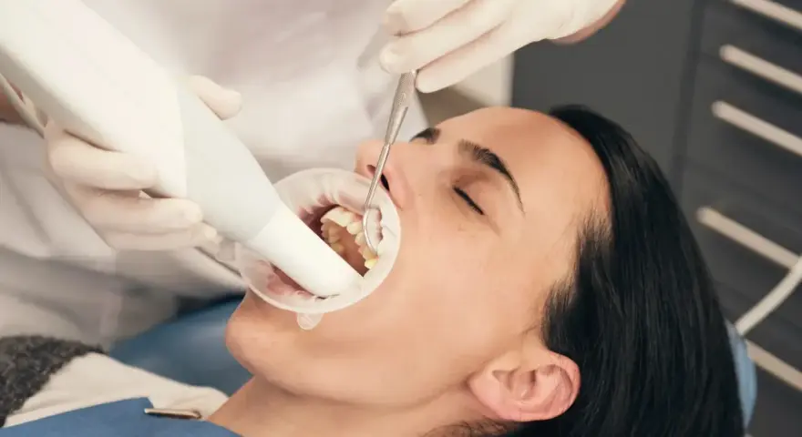 Dentysta bada zęby pacjentki, która używa specjalnej pasty na ruszające się zęby.