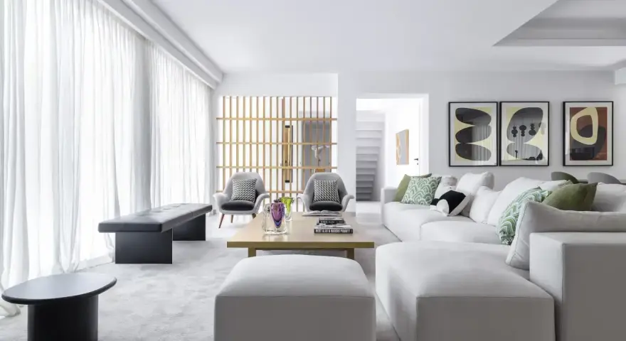 Elegante salón pintado en gris, con sofás blancos, sillones grises y arte abstracto.
