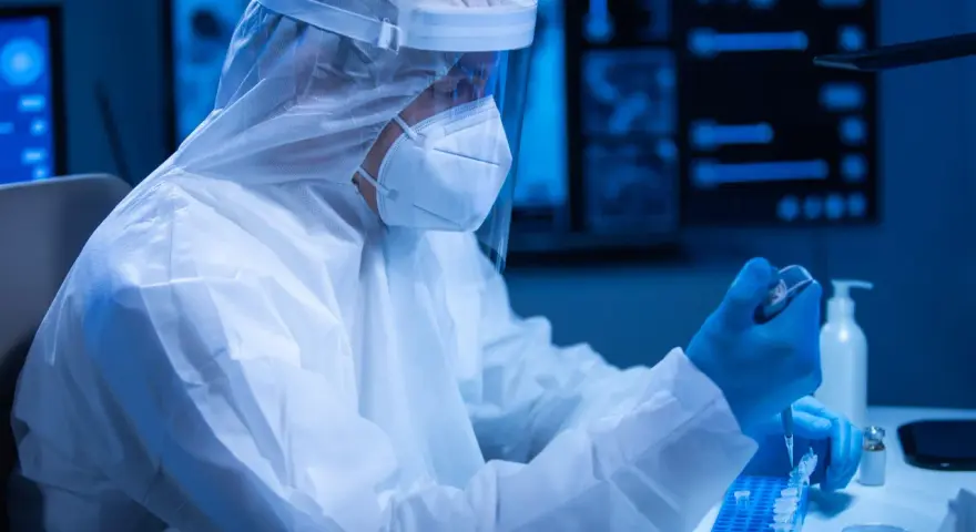 Badacz w kombinezonie ochronnym pracuje w laboratorium, przygotowując próbki. Czas oczekiwania na wynik badania PCR może być różny.