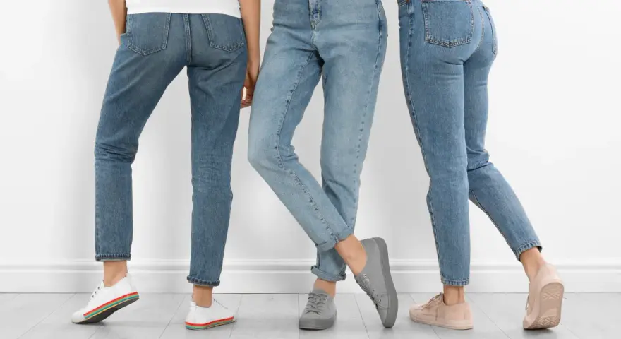 Trzy kobiety w jeansach i sneakersach. Dowiedz się, jak rozciągnąć jeansy, by były idealnie dopasowane.