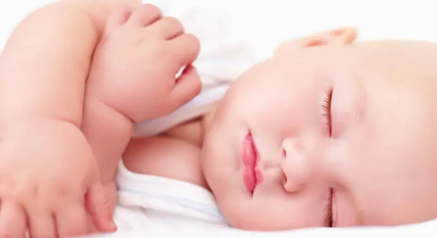 Ein friedlich schlafendes Baby, etwa 4 Monate alt, mit geschlossenen Augen und leicht geöffneten Lippen. Die zarte Haut und die kleinen Händchen sind gut zu erkennen.