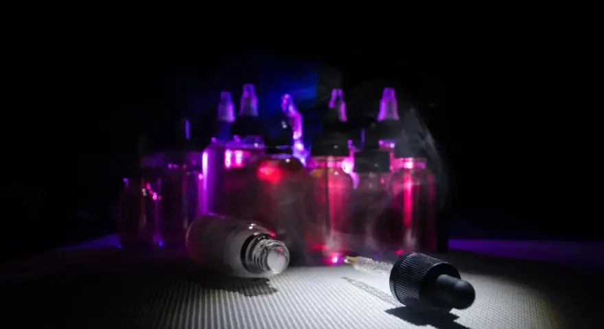 Gotas de nicokit como usar: frascos de líquido para vapear con luz púrpura y vapor.