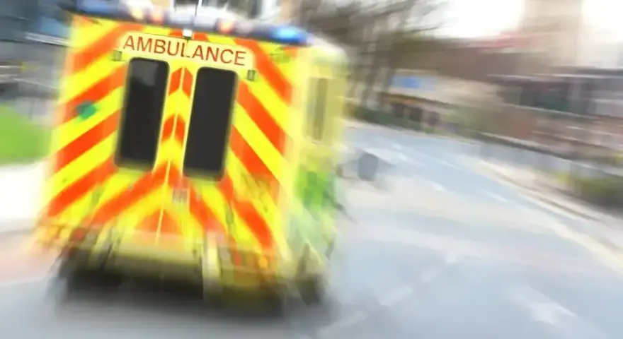 Ambulans w ruchu na drodze, z widocznym napisem AMBULANCE.